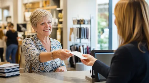 A woman handing a receipt to a clerk at customer service