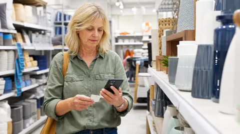 A shopper comparing a sale tag with prices on her phone